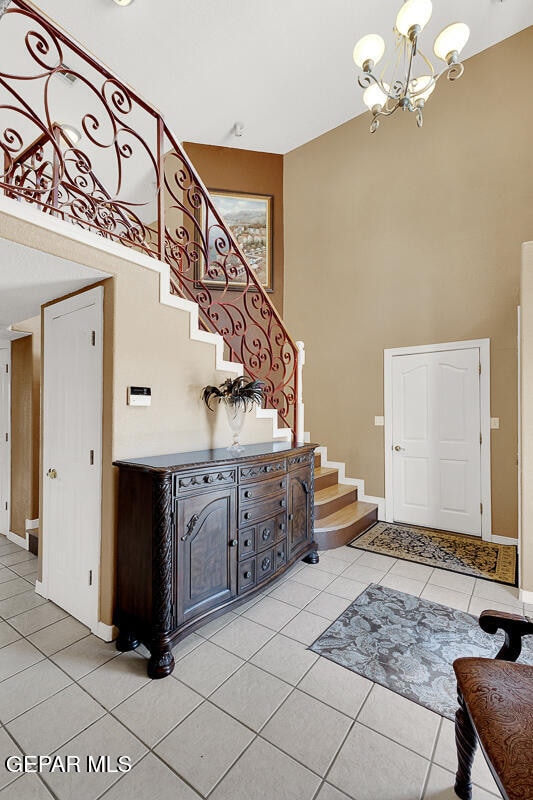 tiled foyer entrance with a towering ceiling and a chandelier