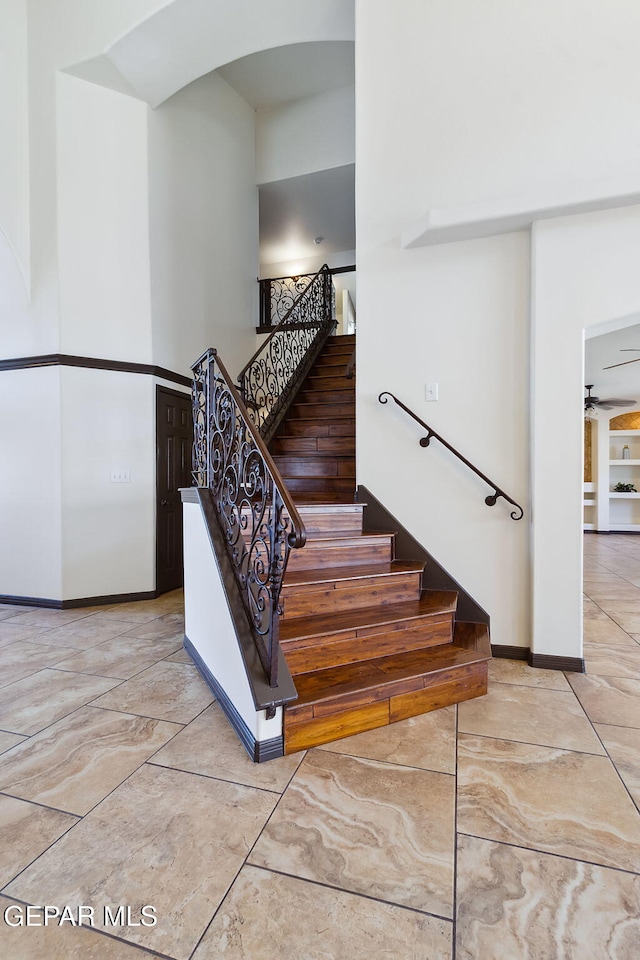 stairway featuring ceiling fan