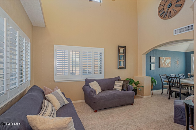 carpeted living room with a towering ceiling