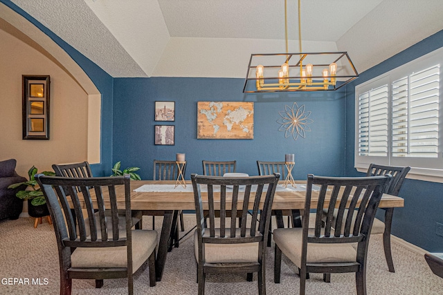 carpeted dining space featuring a textured ceiling, vaulted ceiling, and a notable chandelier