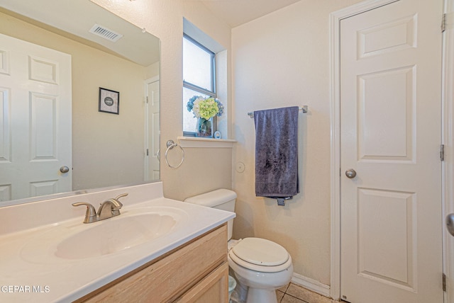 bathroom with toilet, vanity, and tile patterned flooring