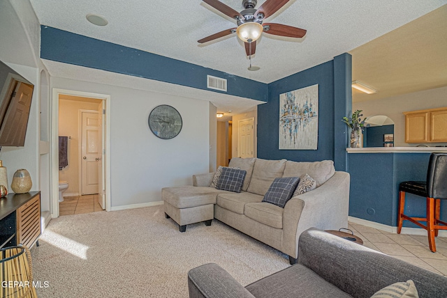 living room featuring a textured ceiling, light colored carpet, and ceiling fan