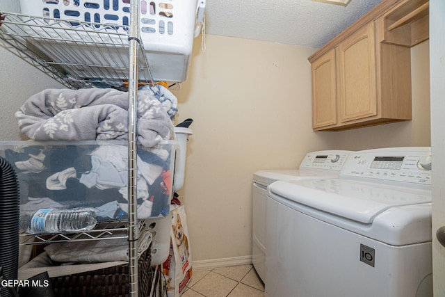 washroom with cabinets, washing machine and dryer, a textured ceiling, and light tile patterned floors