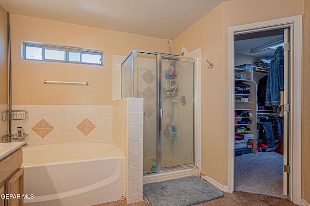 bathroom featuring tile patterned flooring, vanity, a textured ceiling, and separate shower and tub