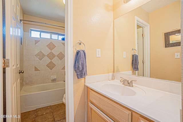 full bathroom with tile patterned floors, vanity, tiled shower / bath combo, and toilet