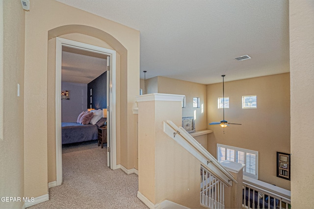 corridor featuring light colored carpet and a textured ceiling