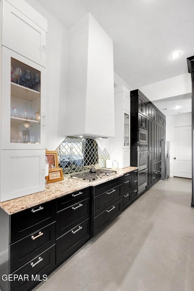 kitchen with tasteful backsplash, white cabinets, and stainless steel appliances