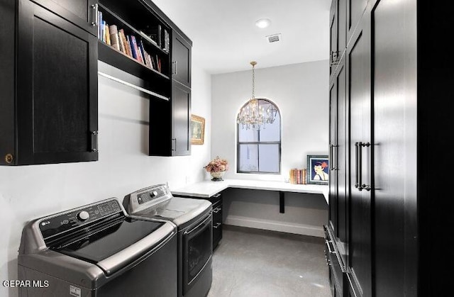 clothes washing area featuring cabinets, a chandelier, and washing machine and clothes dryer