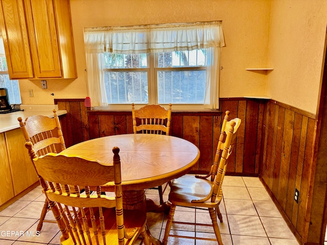 dining room with wood walls and light tile patterned floors
