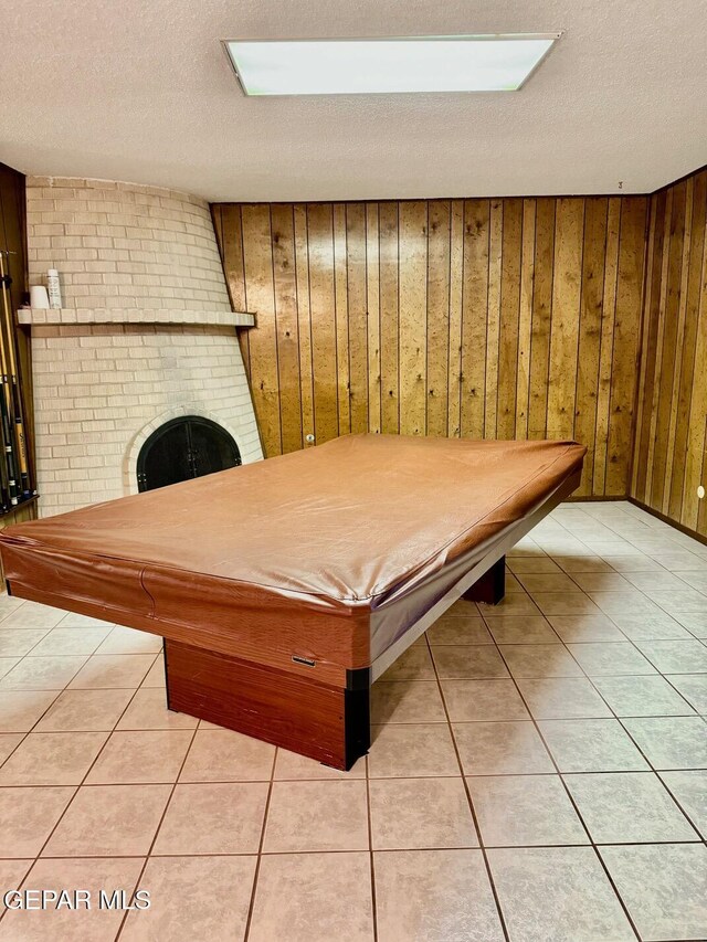 10521 Gaius Dr, El Paso, TX 79924 - game room with billiards table, wooden walls, a textured ceiling, light tile patterned flooring, and a fireplace