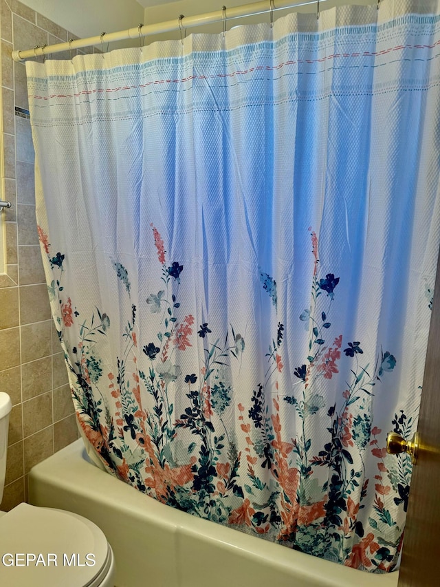 bathroom featuring tile walls and toilet