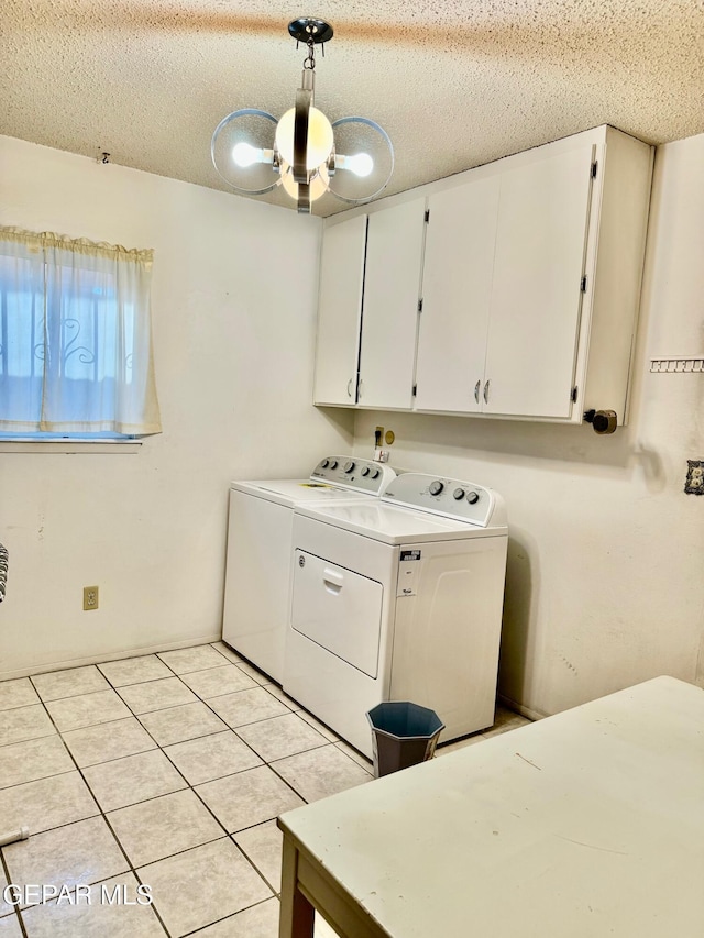 clothes washing area featuring cabinets, light tile patterned floors, a textured ceiling, and washer and dryer