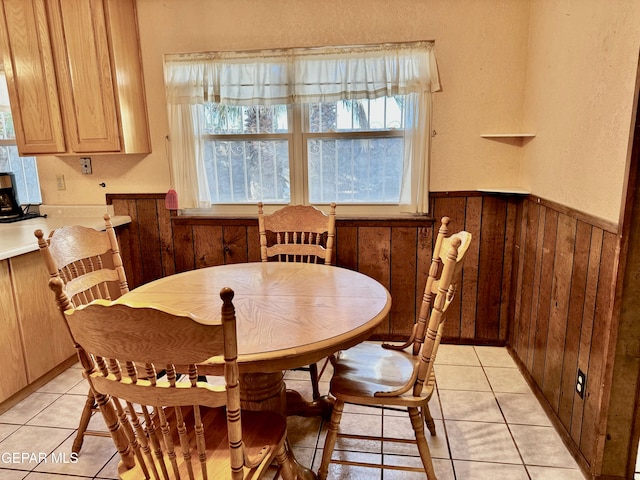 tiled dining area featuring a healthy amount of sunlight and wooden walls