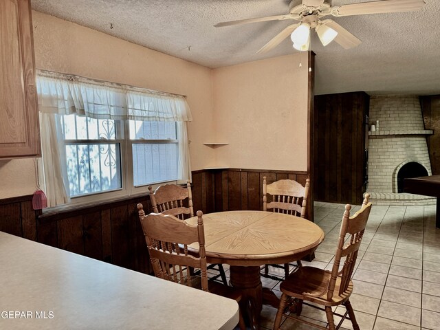 10521 Gaius Dr, El Paso, TX 79924 - dining space featuring a textured ceiling, wood walls, wainscoting, ceiling fan, and light tile patterned flooring