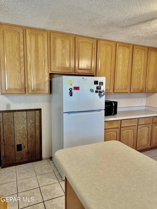 10521 Gaius Dr, El Paso, TX 79924 - kitchen featuring freestanding refrigerator, light countertops, light tile patterned floors, and a textured ceiling
