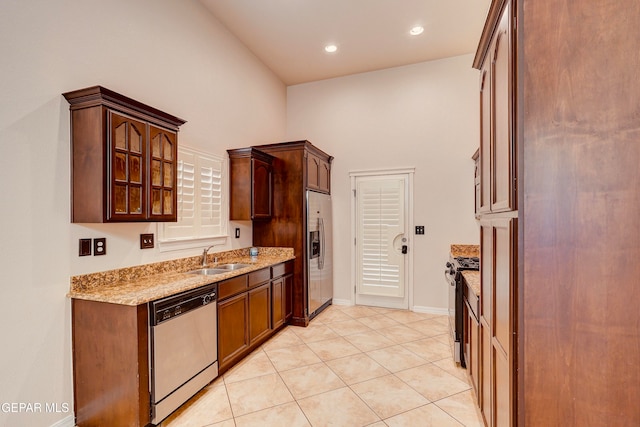 kitchen featuring light stone countertops, sink, high vaulted ceiling, light tile patterned floors, and appliances with stainless steel finishes