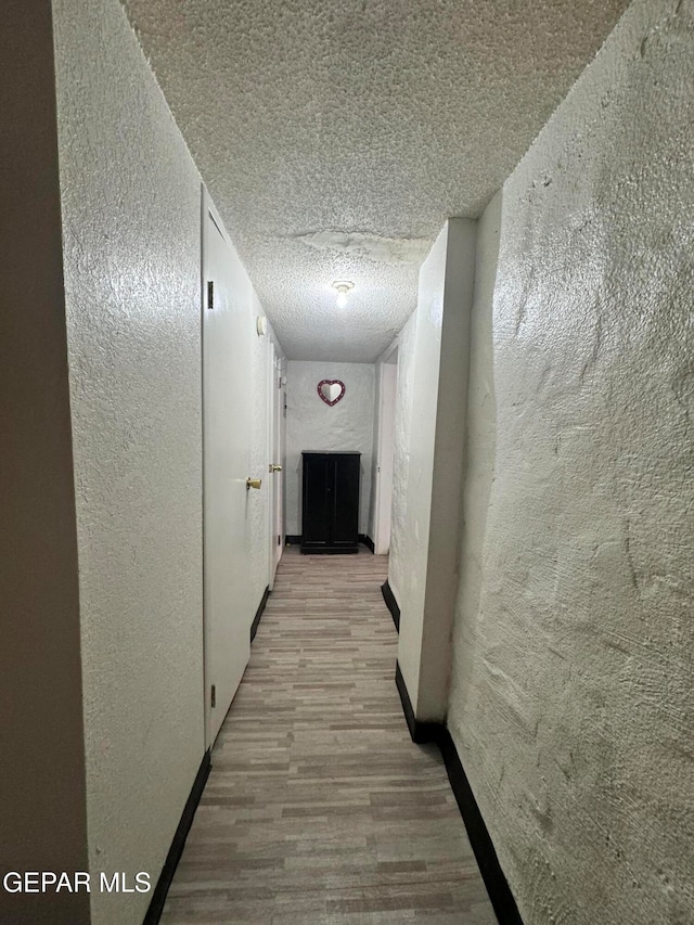 corridor featuring light hardwood / wood-style floors and a textured ceiling