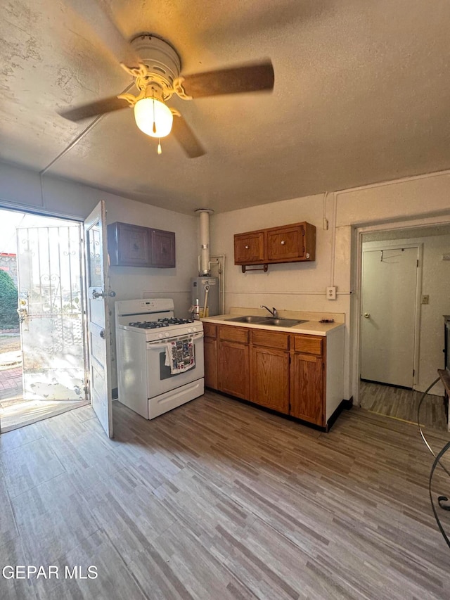 kitchen featuring ceiling fan, white gas stove, water heater, and light wood-type flooring