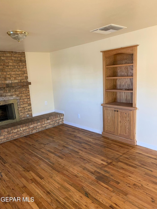 unfurnished living room featuring a fireplace and dark hardwood / wood-style flooring