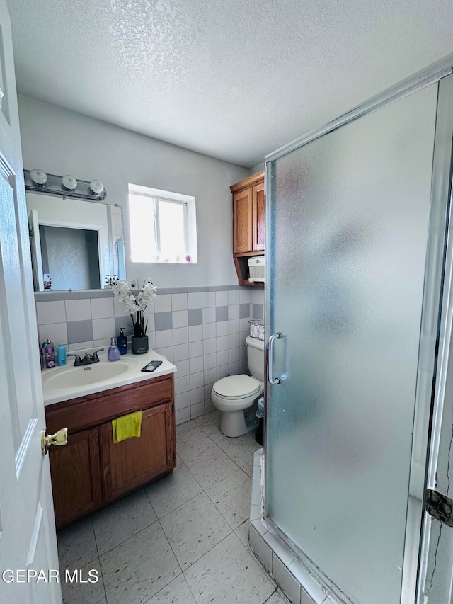 bathroom featuring toilet, tile walls, a textured ceiling, vanity, and a shower with shower door