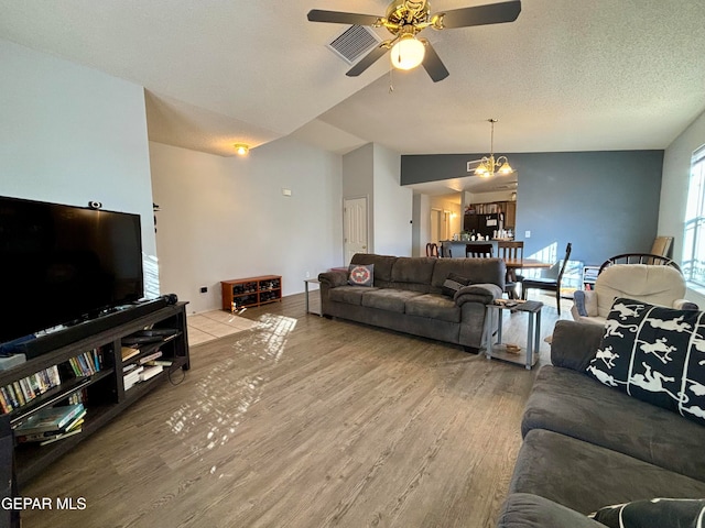 living room featuring a textured ceiling, lofted ceiling, ceiling fan with notable chandelier, and hardwood / wood-style flooring