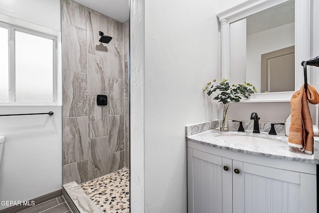 bathroom featuring tiled shower and vanity