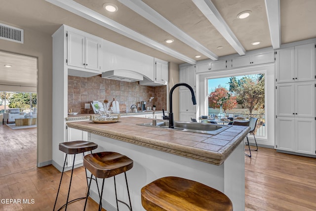 kitchen with sink, white cabinets, and light wood-type flooring