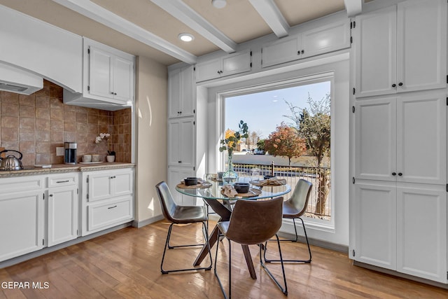 dining area featuring beam ceiling and light wood-type flooring