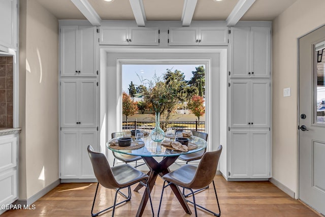 dining room with beamed ceiling and light wood-type flooring