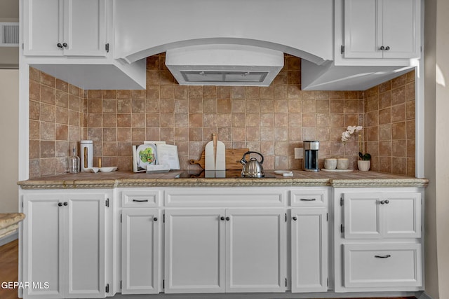 kitchen featuring backsplash, light stone counters, and white cabinets