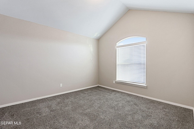 empty room featuring dark colored carpet and vaulted ceiling