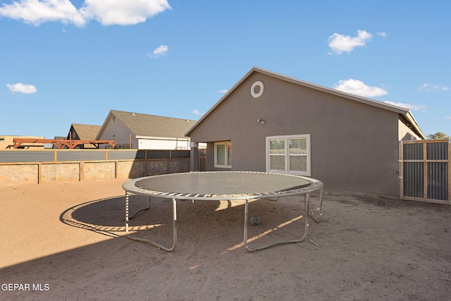 rear view of property featuring a trampoline