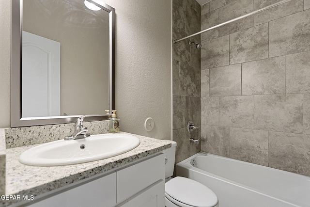 full bathroom featuring tiled shower / bath, vanity, and toilet