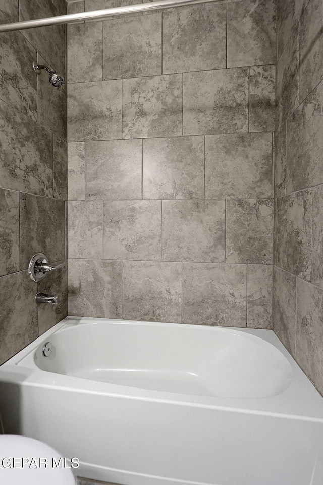 bathroom featuring tiled shower / bath and toilet