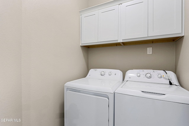 laundry room featuring washing machine and clothes dryer and cabinets