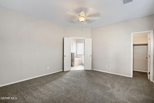 unfurnished bedroom with ensuite bath, light carpet, ceiling fan, a closet, and a walk in closet