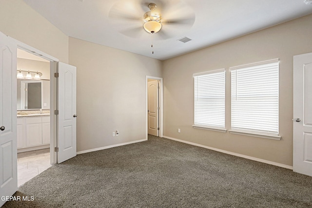 unfurnished bedroom with connected bathroom, carpet flooring, and ceiling fan