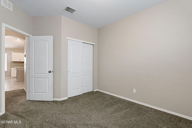 unfurnished bedroom with dark colored carpet and a closet