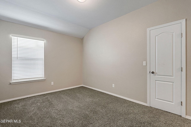 carpeted empty room with vaulted ceiling