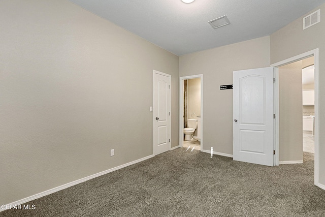 unfurnished bedroom with connected bathroom and dark colored carpet