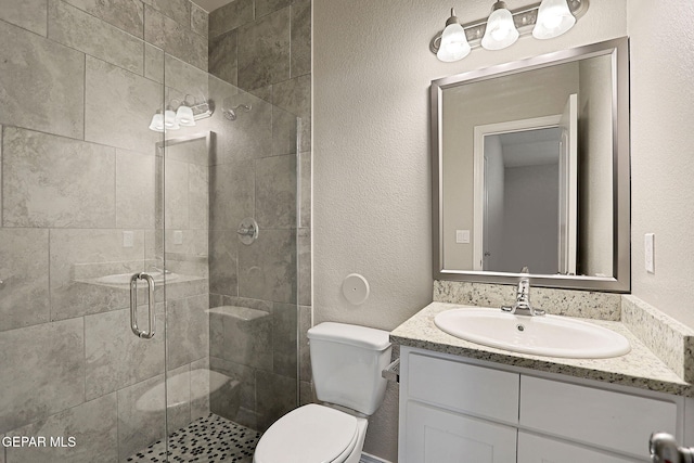 bathroom featuring a shower with shower door, vanity, and toilet