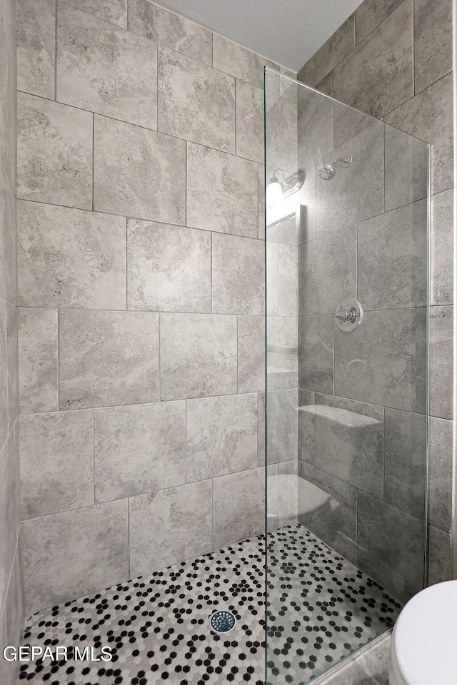 bathroom featuring toilet and a tile shower