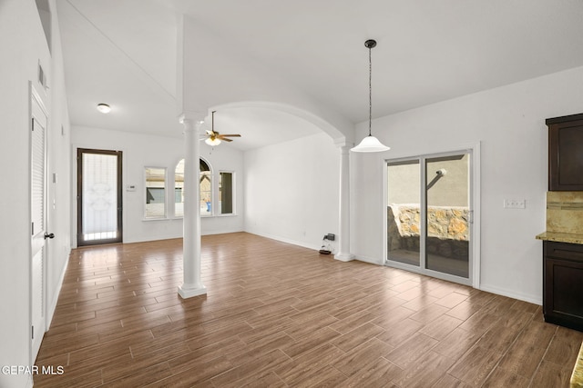 unfurnished living room with ceiling fan, wood-type flooring, and ornate columns