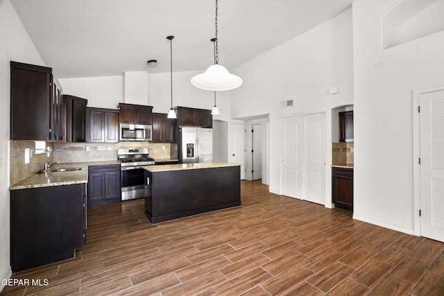 kitchen featuring stainless steel appliances, hanging light fixtures, high vaulted ceiling, dark hardwood / wood-style floors, and a kitchen island