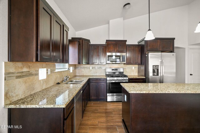 kitchen with backsplash, appliances with stainless steel finishes, decorative light fixtures, dark hardwood / wood-style floors, and light stone countertops