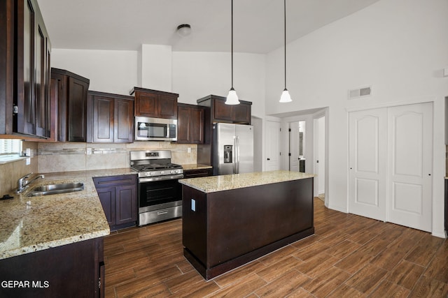 kitchen featuring a kitchen island, appliances with stainless steel finishes, dark hardwood / wood-style flooring, pendant lighting, and sink