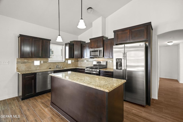 kitchen featuring stainless steel appliances, pendant lighting, dark wood-type flooring, and vaulted ceiling