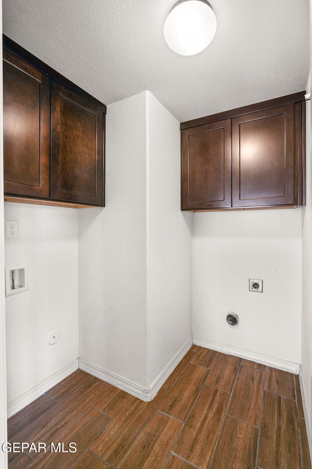 washroom with hookup for an electric dryer, dark hardwood / wood-style flooring, cabinets, a textured ceiling, and washer hookup