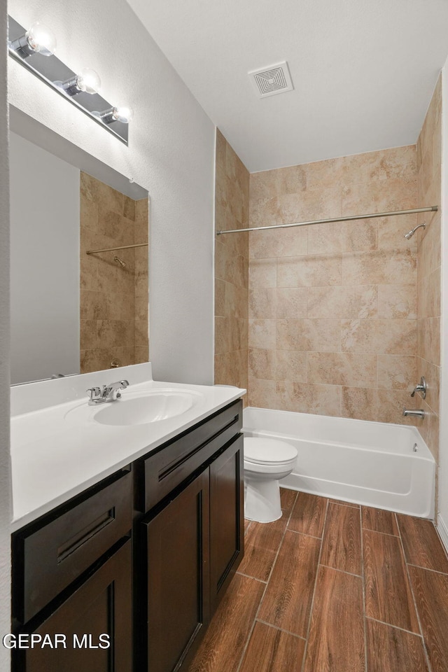 full bathroom featuring tiled shower / bath, toilet, and vanity