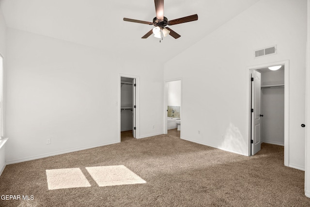 unfurnished bedroom with carpet flooring, ensuite bath, high vaulted ceiling, ceiling fan, and a spacious closet